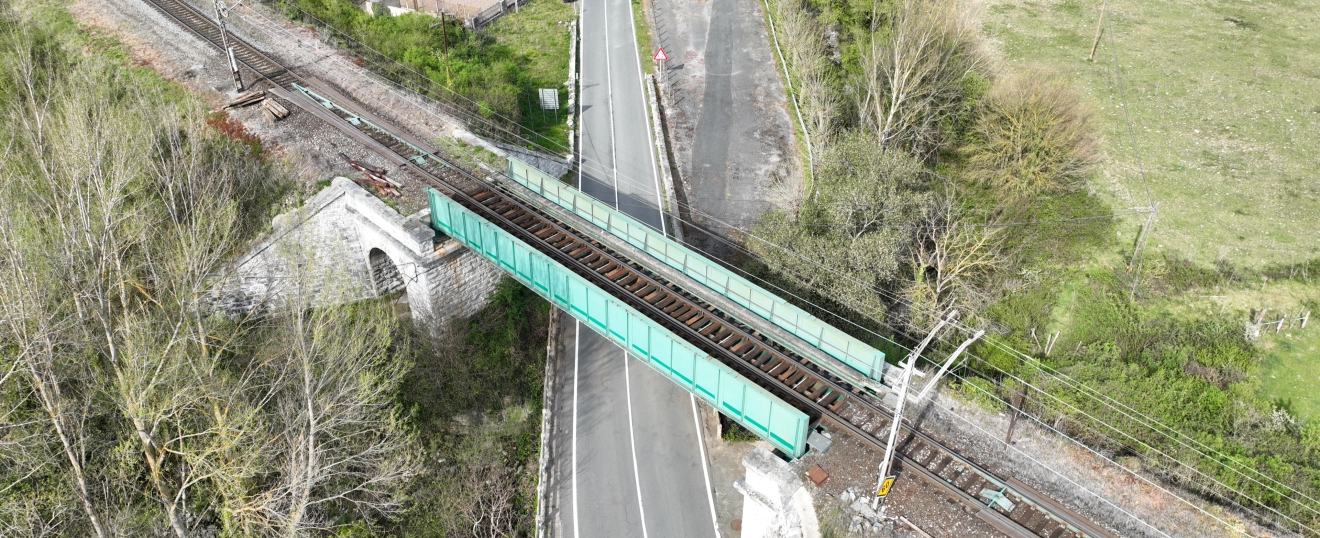 Puente metálico verde entre la carretera y las vías. Fotografía aérea con dron de VISUAIR