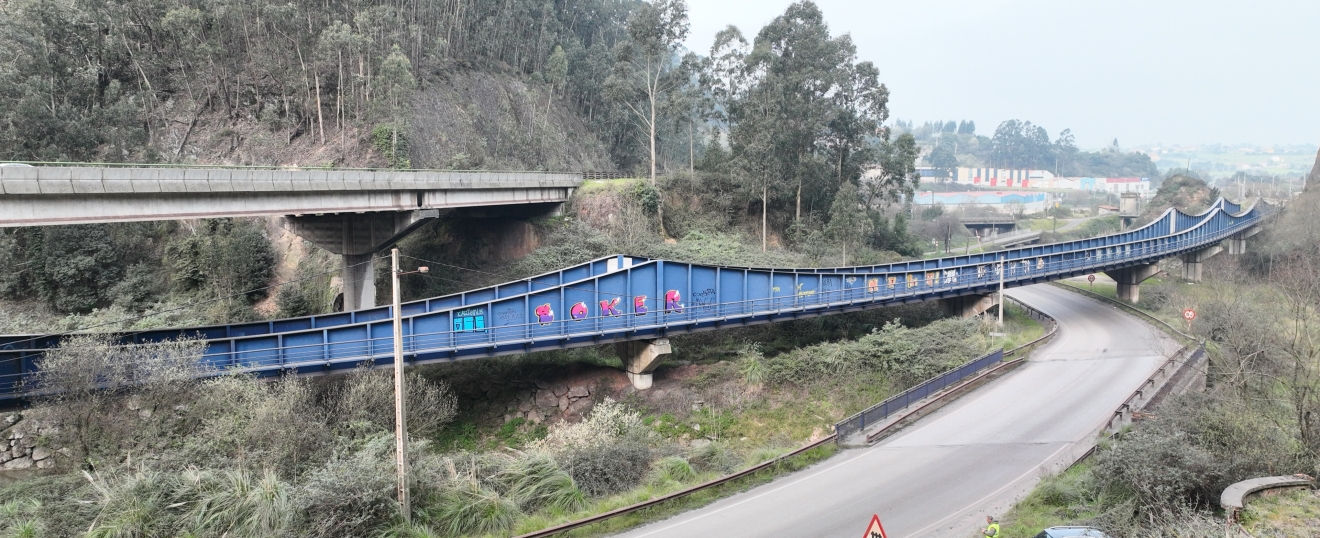 Puente metálico azul en curva junto a la carretera. Fotografía aérea con dron de VISUAIR