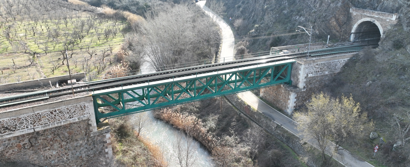 Puente verde sobre el río entre túneles y montaña. Fotografía aérea con dron de VISUAIR